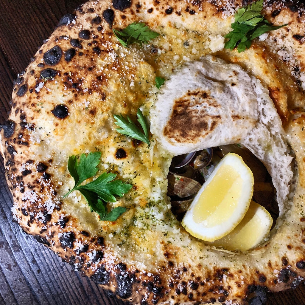A picture of a white sauce based pizza on a wooden table to reflect our blog article title named 'Wine Pairings for our Favorite Takeout in LA'.