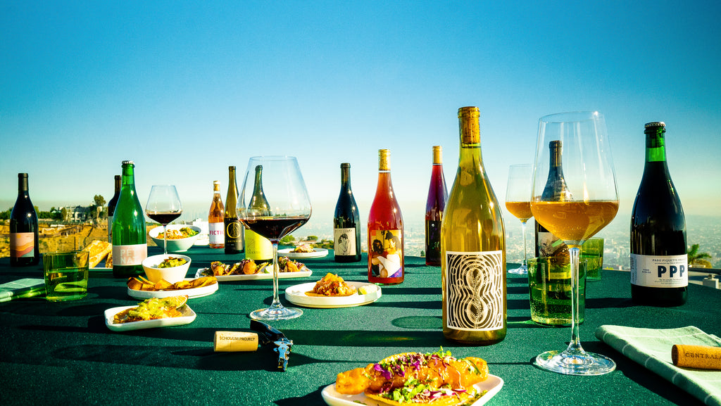 Table with green table cloth displaying mexican food and natural wines